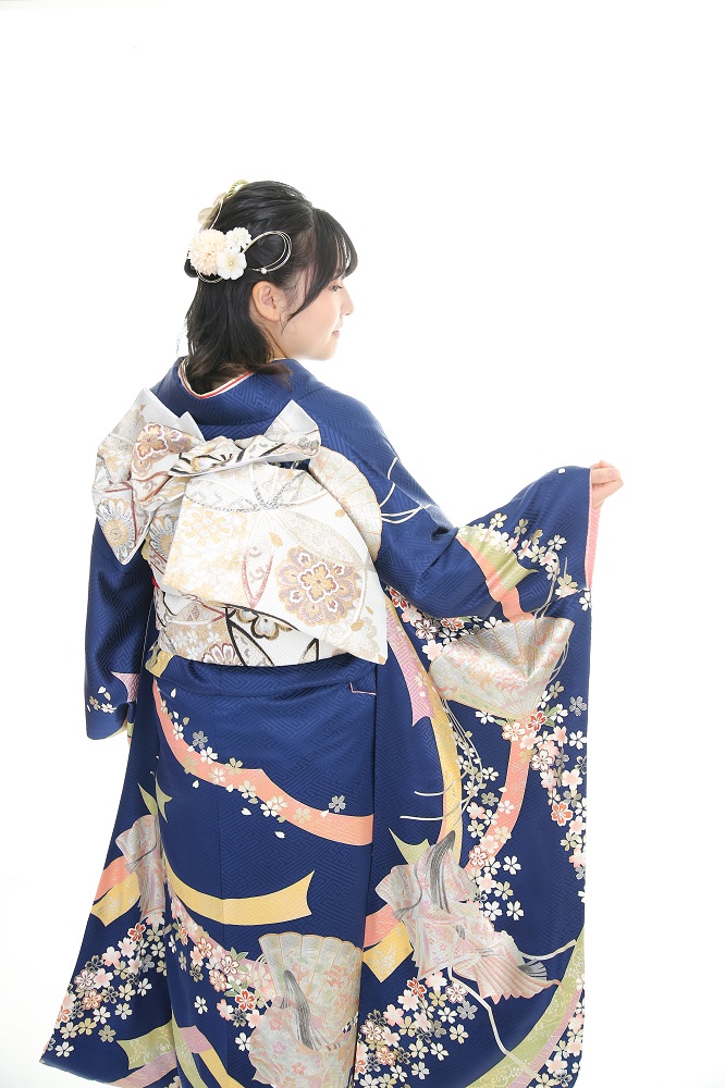 紺地のシンプルな振袖にシルバーの帯を締めた後ろ姿の女性